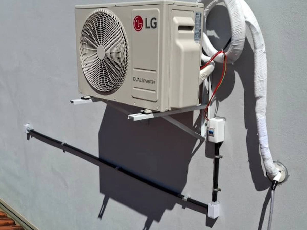Técnico instalando sistema de climatização em edificação comercial